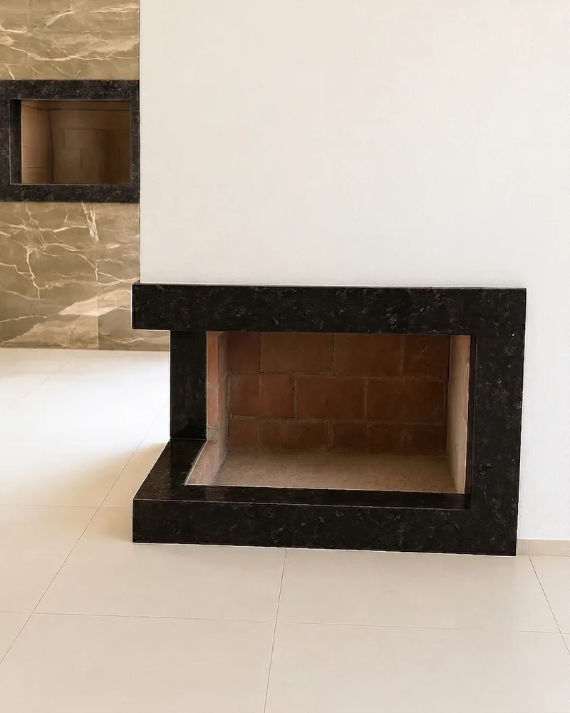 Lareira revestida em granito preto, com moldura e base em pedra sobre piso claro